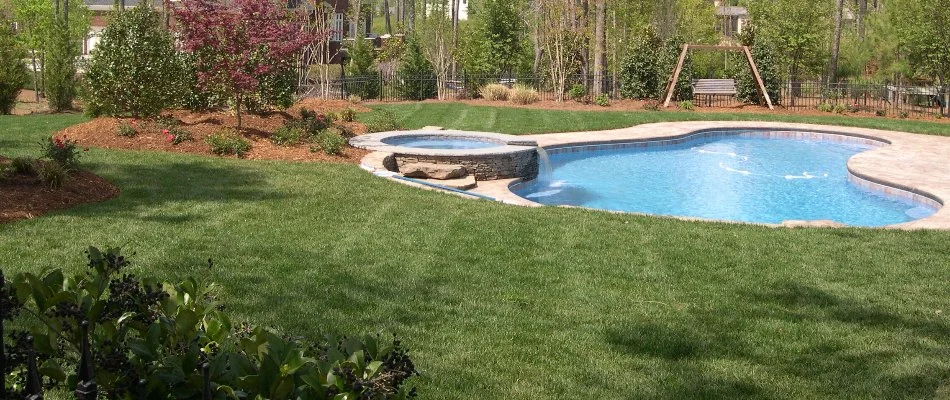 Maintained lawn and landscape around a pool in Garner, NC.
