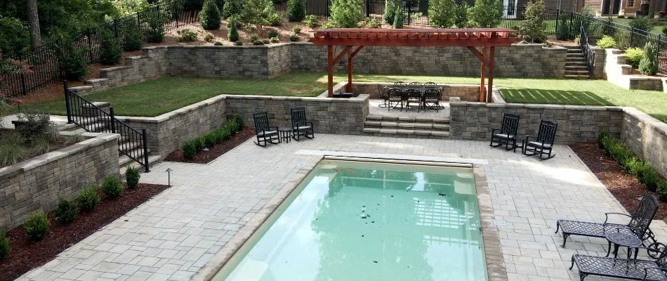 Pool in Clayton, NC, with a paver patio, retaining walls, and pergola.